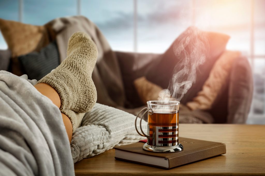 Persona descansado sobre un sillón confortable con una taza de té sobre una mesa