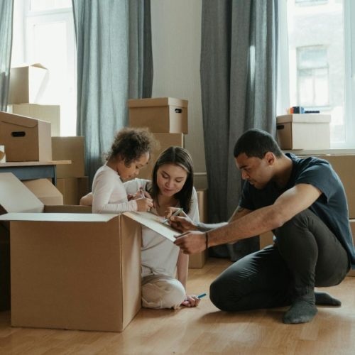 Una mujer, un hombre y una niña desempacando cosas de cajas